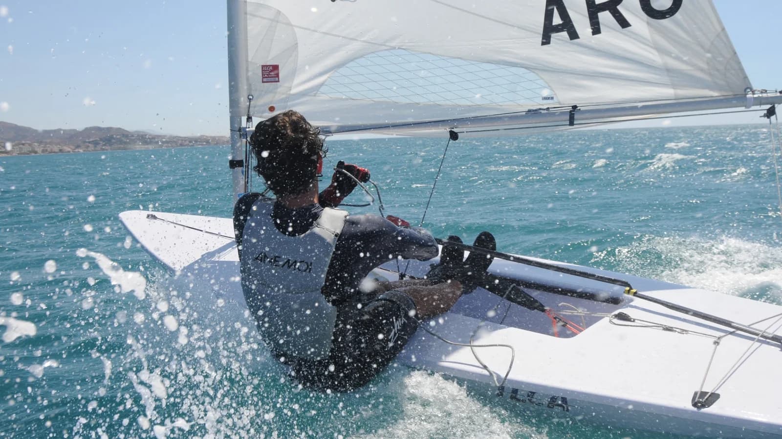 Nicolás Schioppa sailing a racing dinghy, surrounded by spray.
